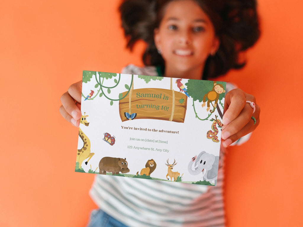 Person holding a children's birthday invitation card with jungle animal illustrations on an orange background