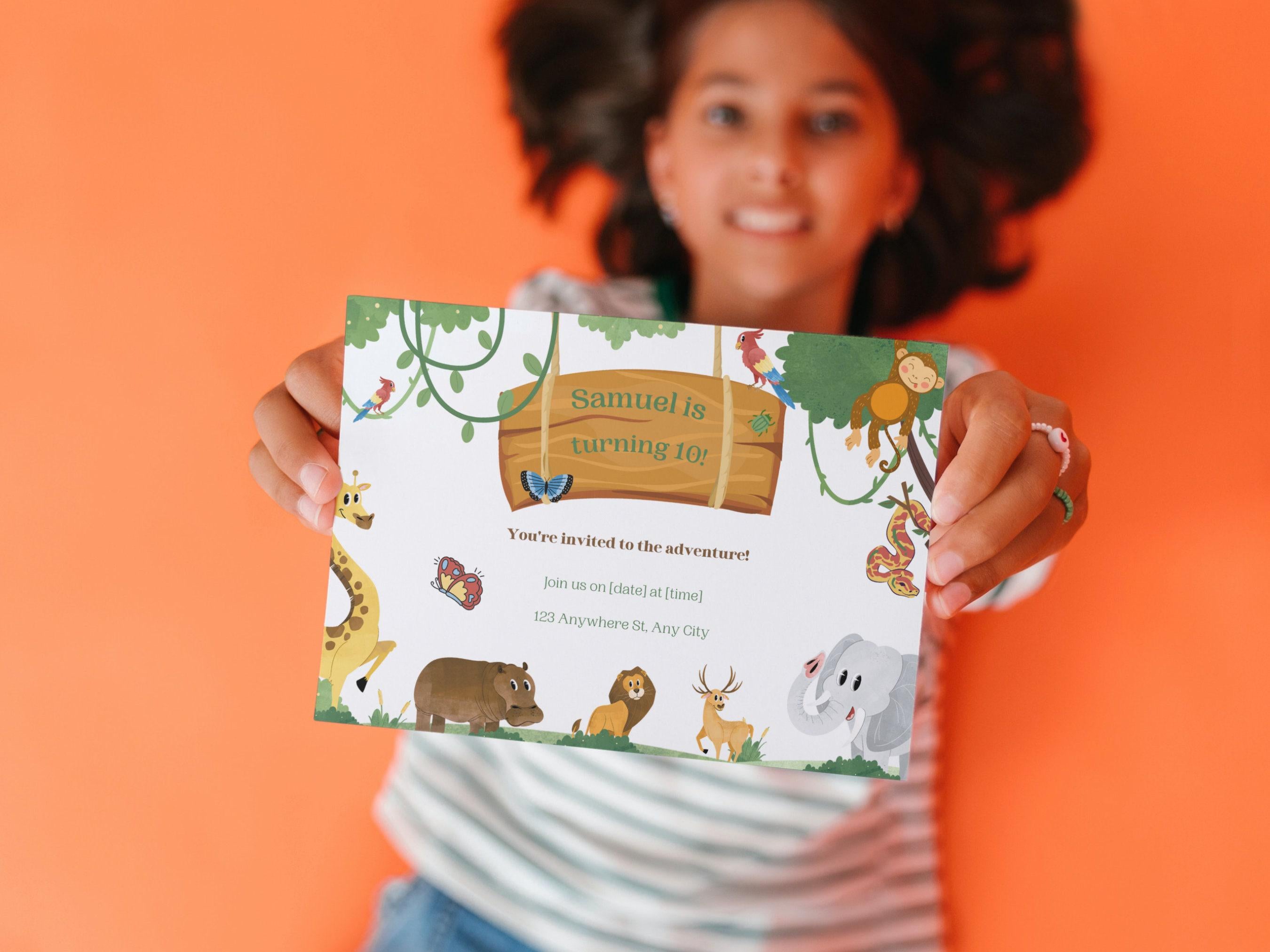 Person holding a children's birthday invitation card with jungle animal illustrations on an orange background